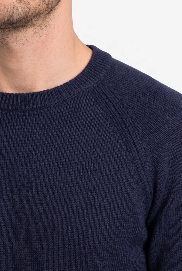 Detail of the ribbed crew neck and raglan sleeve of the PELOT made-to-measure sweater, worn by a man.